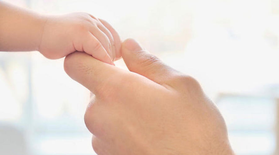Young dad holding hand of his little son, closeup